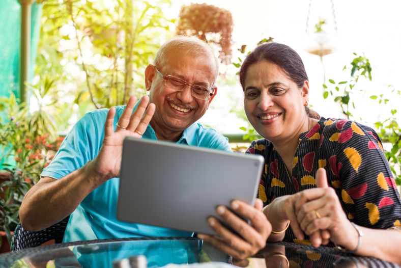 grandparents watching tablet device smiling and waving 
