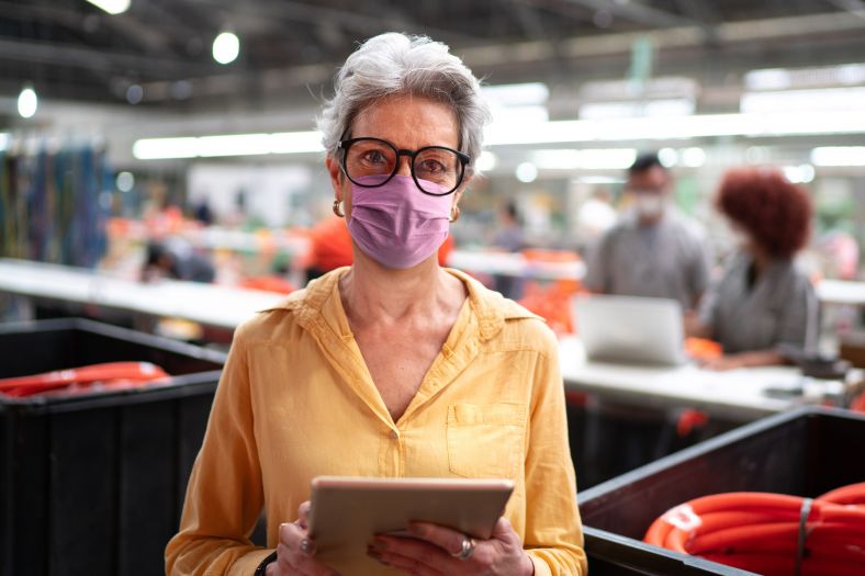 Woman wearing a purple mask, holding a tablet