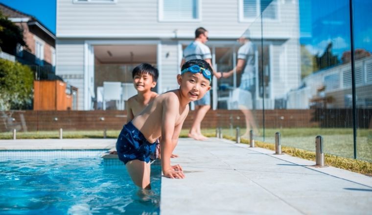 Two boys jumping into a swimming pool