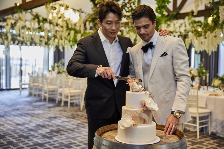 Two grooms cutting their wedding cake.