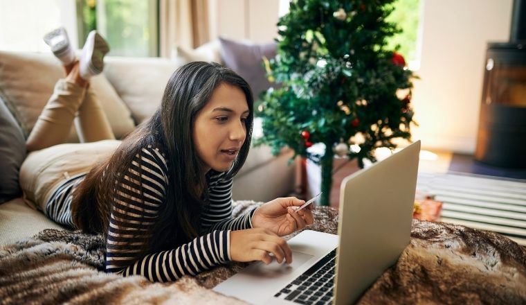 Young woman Christmas shopping online in her living room.