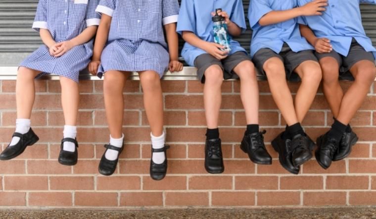 Primary school children sitting on a wall