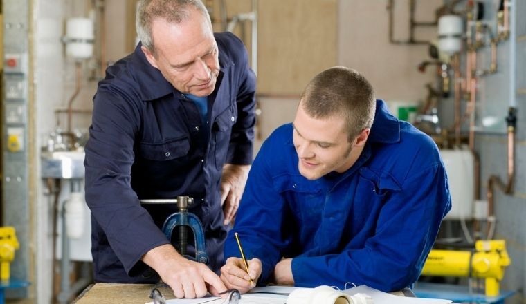 A plumber instructing an apprentice on the job