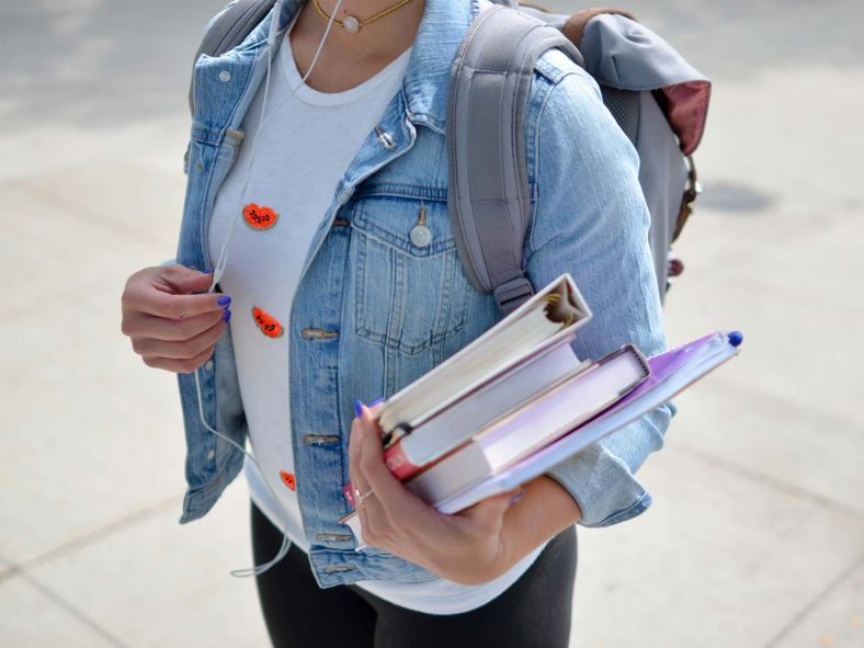 Young adult woman with backpack and textbooks