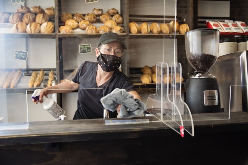 Bakery owner wiping down surfaces wearing mask