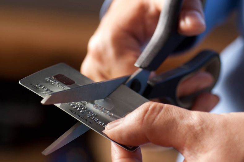 A credit card is being cut in half by a pair of scissors