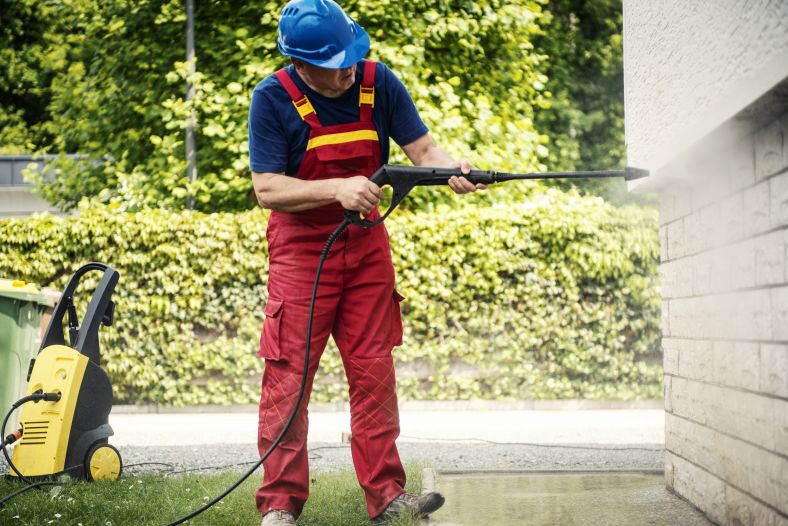 Man cleaning with a high pressure hose.