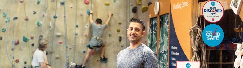 Rock climbing business owner at the counter of his gym accepting NSW vouchers