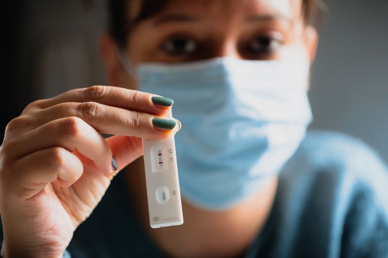 image of someone holding a positive rapid antigen test