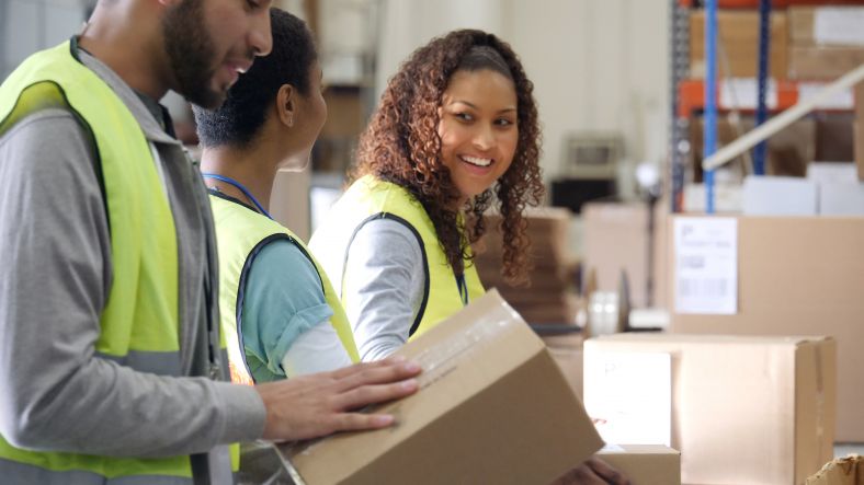 Three people packing boxes in workplace