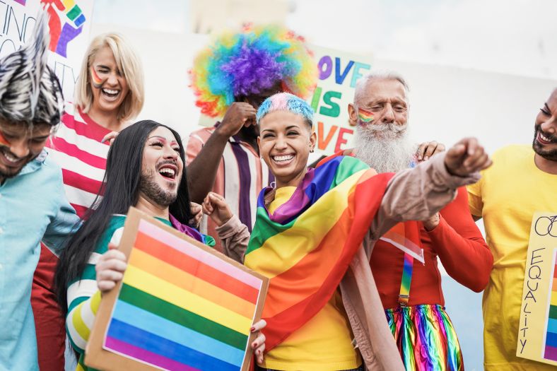 People from different generations have fun at an LGBTQI+ pride parade with banner.