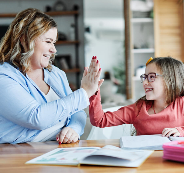 Mother and daughter hi-fiving while doing homework together