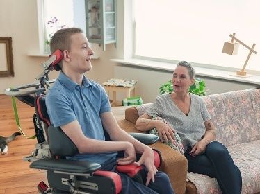 boy in wheelchair and woman on couch in conversation