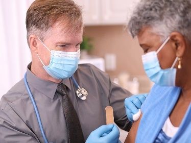 doctor administering vaccine to older woman