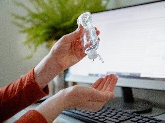 woman using hand sanitiser at her work desk
