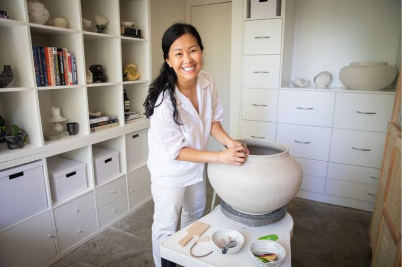 A woman inside her studio makes a clay vase