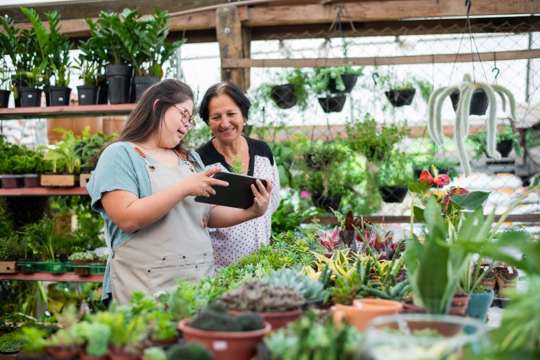 Young worker and manager looking at a tablet working in a garden centre