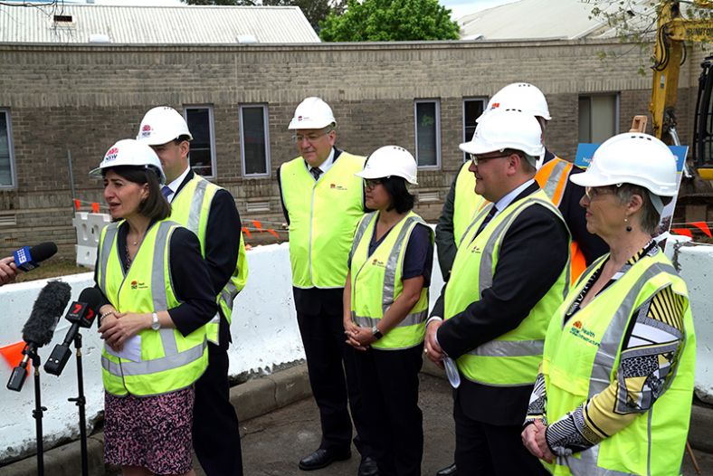 Group of 7 men and women wearing hard hats and fluoro vests