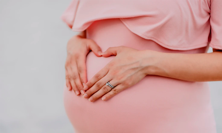 Closeup photo of pregnant belly in pink dress