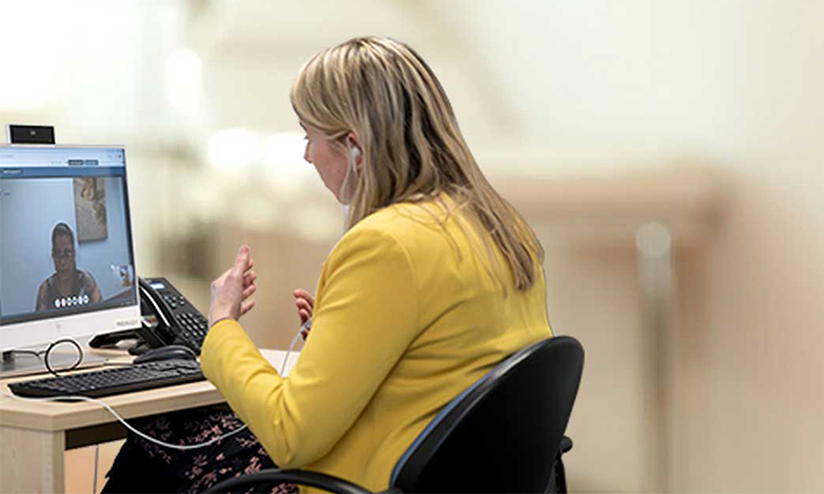Woman sitting at desk talking to a woman on computer screen