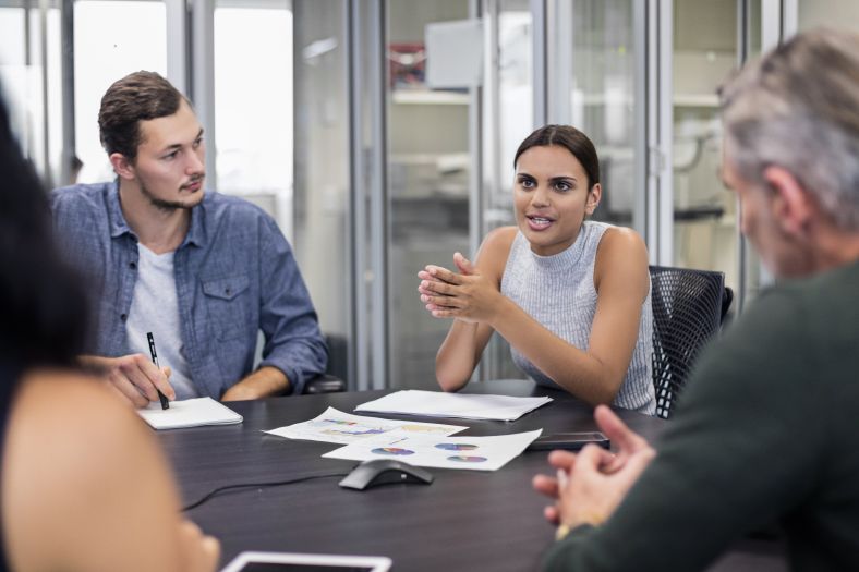 Image of girl sitting around table at a meeting talking to colleagues 