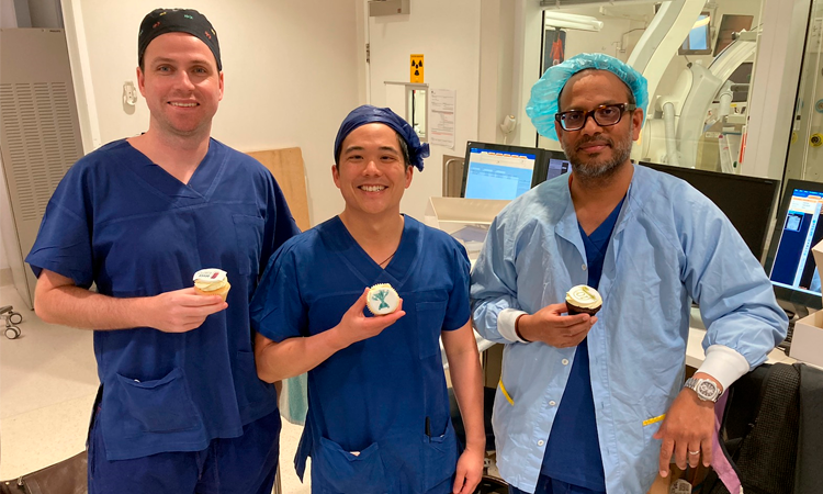 Three smiling doctors holding cupcakes