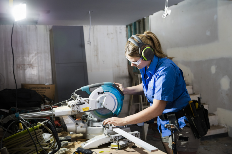 Female tradie cutting timber with a circular saw