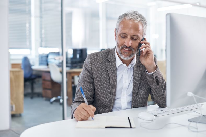 Image of man doing paperwork while on the phone