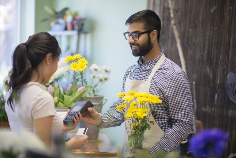 Male florist holding card payment machine for customer 