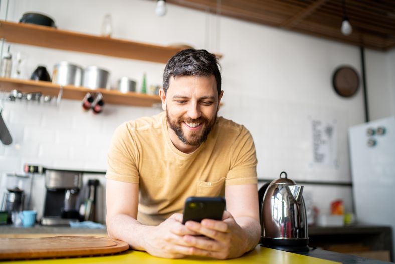 man at cafe counter looking at smart phone