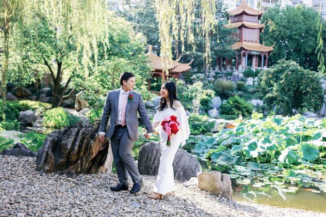 Wedding couple holding hands by the pond at the Chinese Friendship Garden