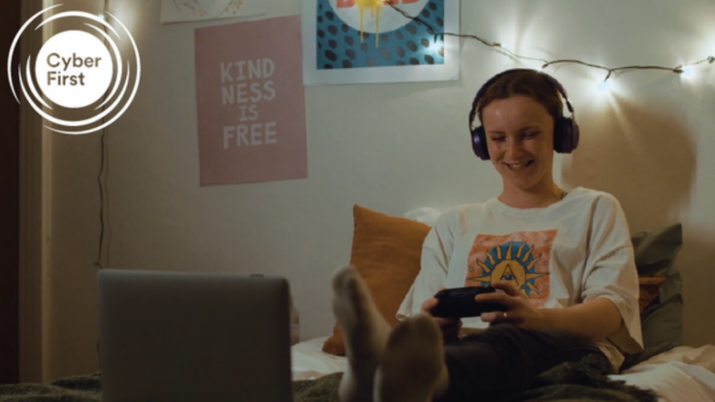 girl sitting on bed with a laptop and headphones and smiling
