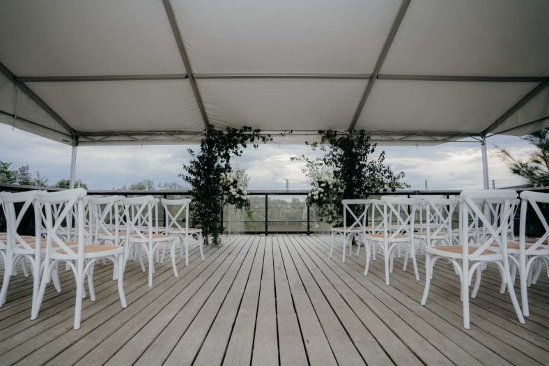 An example of styling for the ceremony showing greenery and white chairs