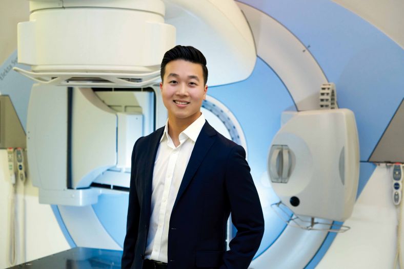 Dr Kevin Jang standing in front of a radiation therapy device