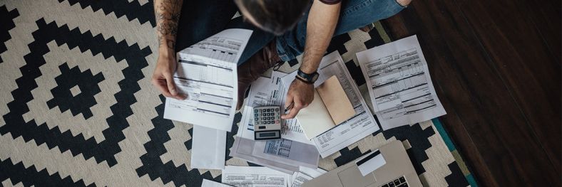 Person looking at bills spread-out across the floor