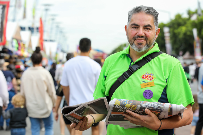 smiling volunteer handing out show guides at the easter show
