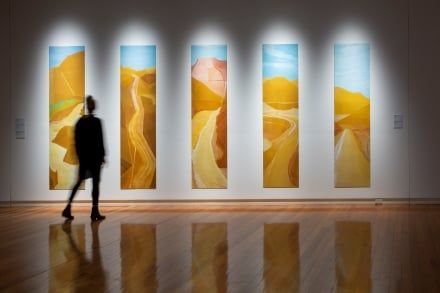 Artistic photo of person silhouetted walking in front of image wall in art gallery