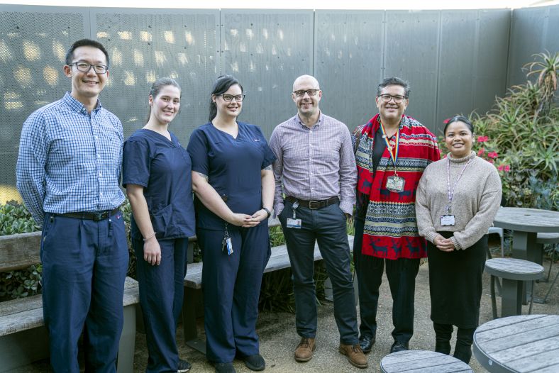 Graham Miller and members of the Mental Health team stand together in a courtyard, smiling for the camera