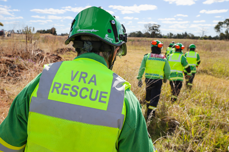 over the shoulder shot of a group of rescue volunteers walking through grassland