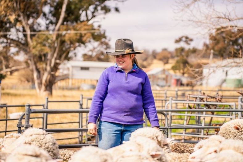 A female grazier in field with sheep
