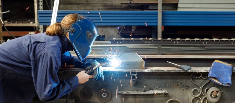 Woman in protective gear welding