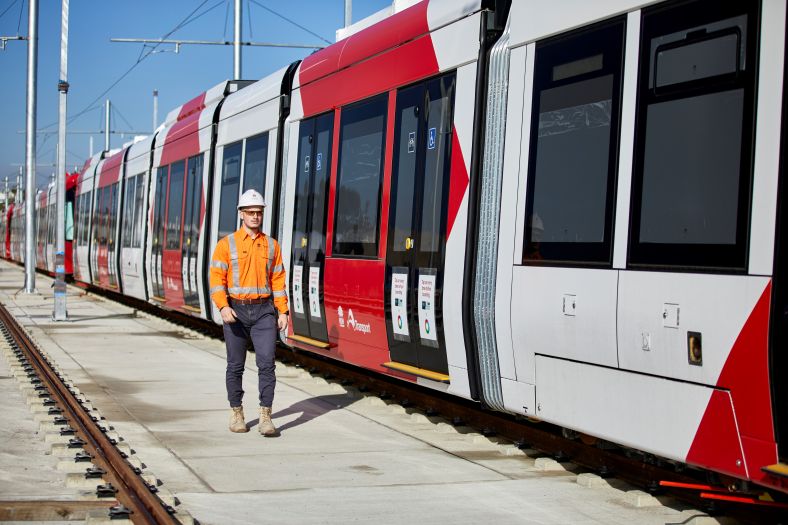 A worker poses alongside one of the new Light Rail Vehicles in the stabling and maintenance facility.