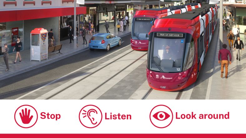 Two red trams can be seen in a busy urban streetscape on the right hand side of iamge a blue car is in the centre and people are walking along sidewalks on either side of the image