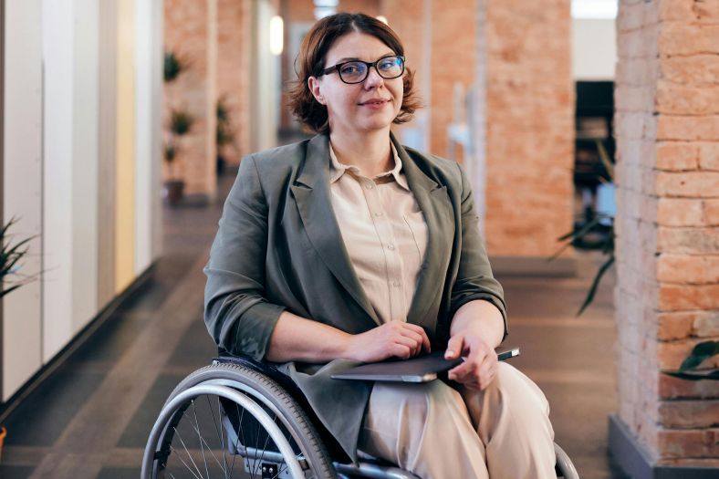 A young woman sat in a wheelchair in a creative office environment.
