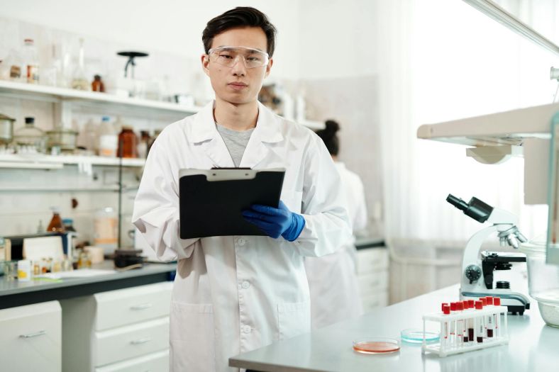 A man stands in a laboratory holding a clipboard.