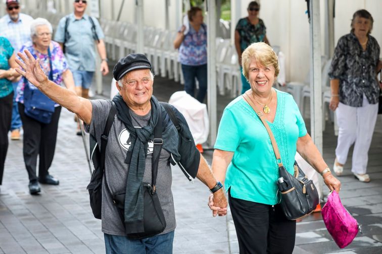 Couple waving as they walk towards Seniors Expo