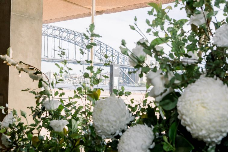 White and green coloured floral arrangement with Sydney Harbour Bridge in the background.