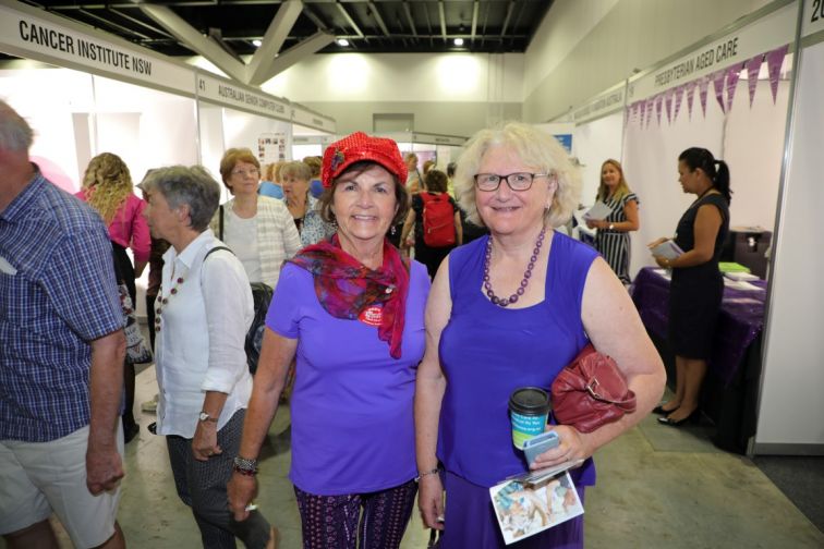 Ladies in purple stop, pose and smile as they mingle past exhibitors