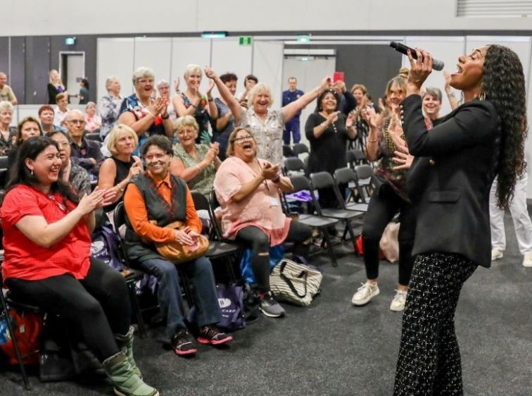 Ladies waving arms and joining in excitedly with Paulini performing