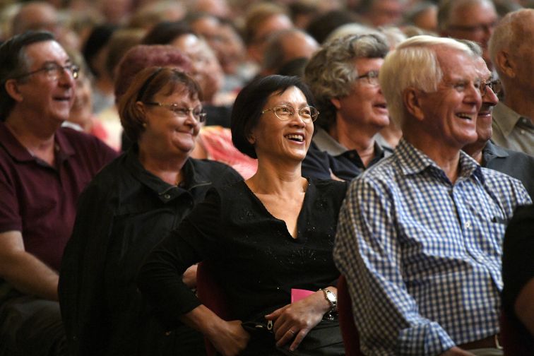 Audience members beam and chuckle as they watch stage at Seniors Comedy Show